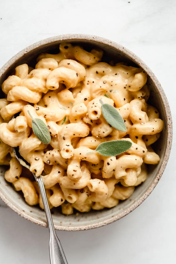 butternut squash mac and cheese in a ceramic bowl with a spoon in it