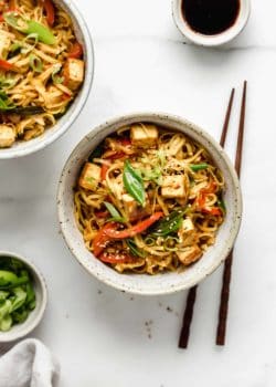 a ceramic bowl filled with Singapore noodles and chopsticks on the side