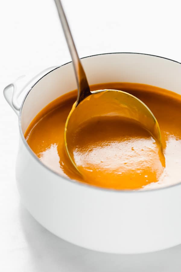 A ladle scooping out a spoonful of butternut squash soup