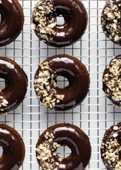 nine donuts topped with chocolate glaze on a silver cooling rack