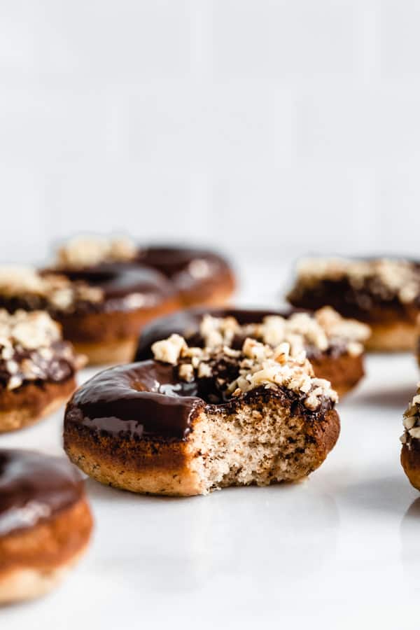 a side view of a banana bread donut topped with chocolate glaze with a bite taken out of it