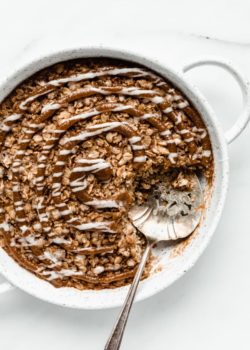 cinnamon roll baked oatmeal in a round baking dish with a serving spoon in it