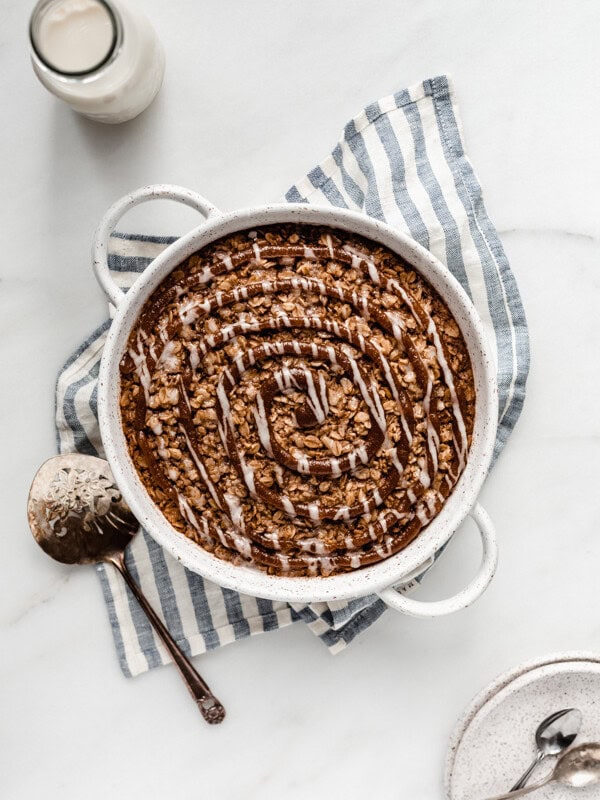 baked oatmeal in a round baking dish on a striped blue napkin topped with cinnamon sugar swirl