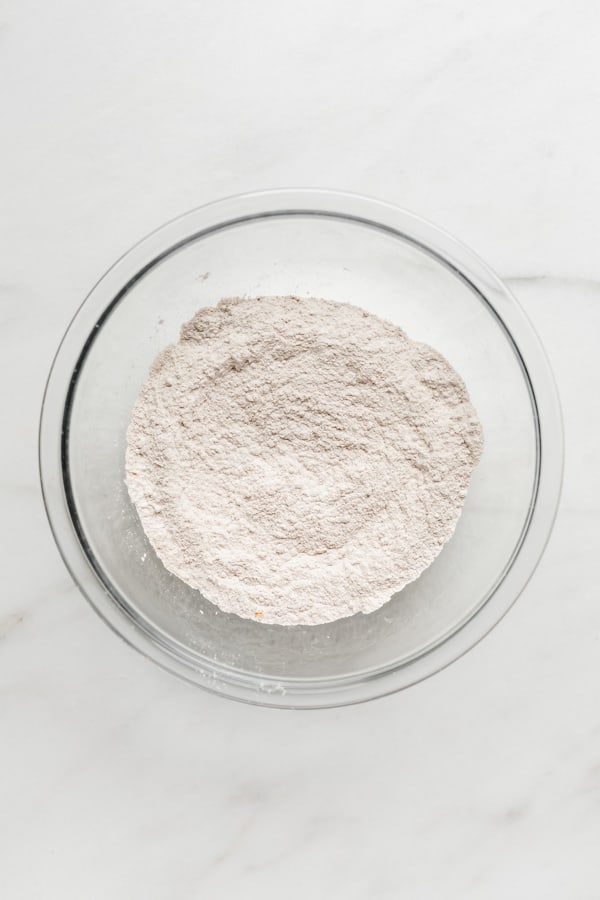 a clear mixing bowl with flour, baking powder and baking soda in it