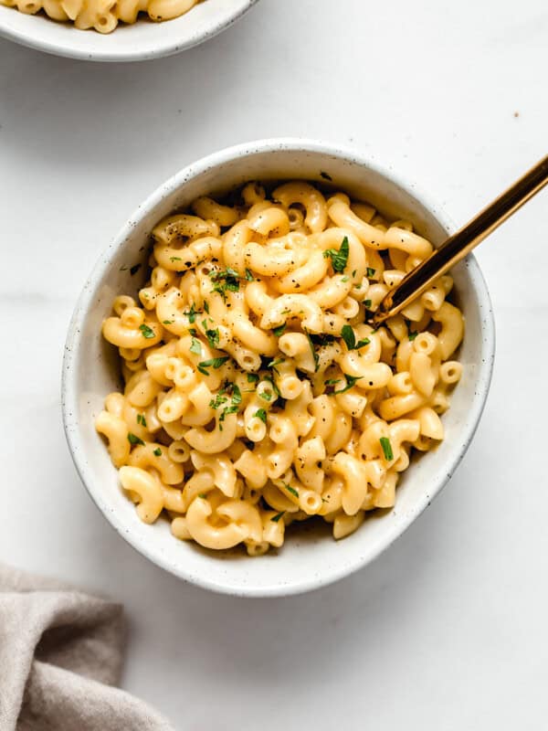 a bowl of mac and cheese with a gold fork in it