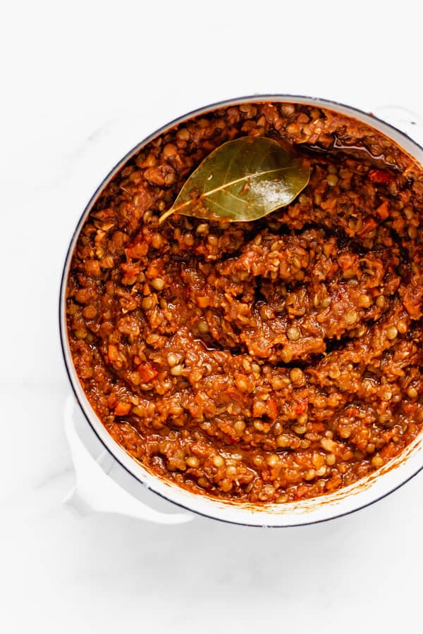 a pot filled with lentil bolognese and a bay leaf on top