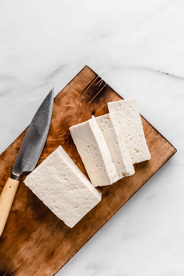 tofu sliced on a wooden cutting board