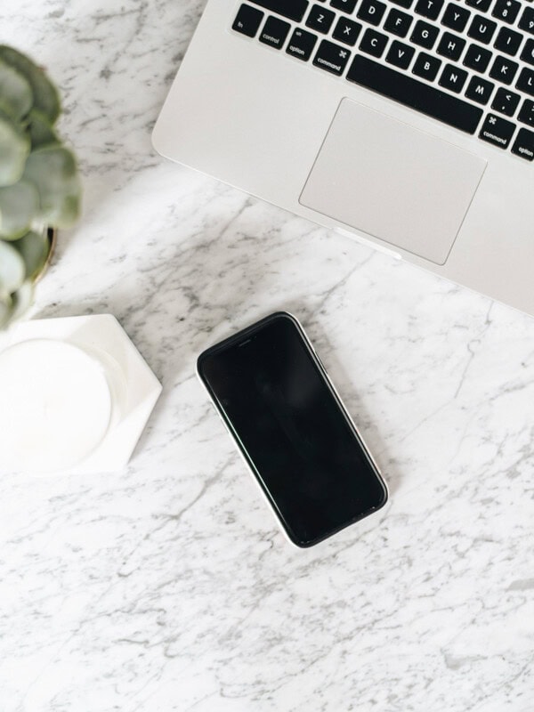 an iphone and laptop on a marble table