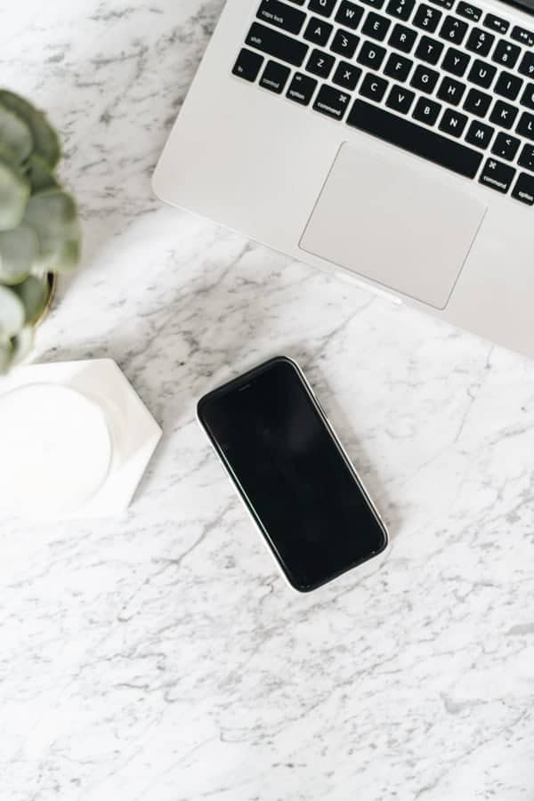 an iphone and laptop on a marble table