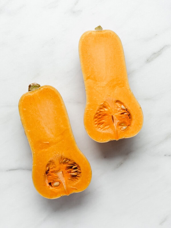 a half of a butternut squash roasted in a white roasting pan