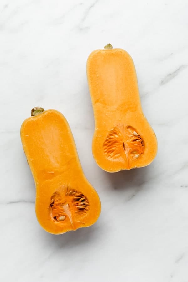 a half of a butternut squash roasted in a white roasting pan