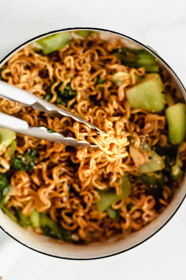 Tongs scooping up ramen noodle stir fry