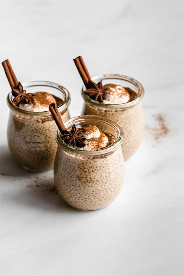 three cups of chai latte chia pudding with cinnamon sticks in them