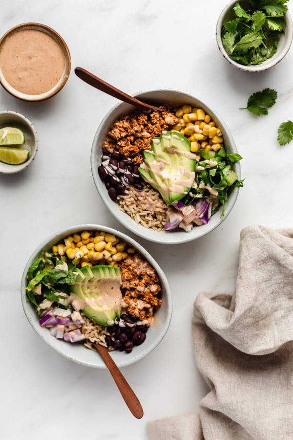 two burrito bowls of chipotle sofritas with a side of chipotle mayo and limes