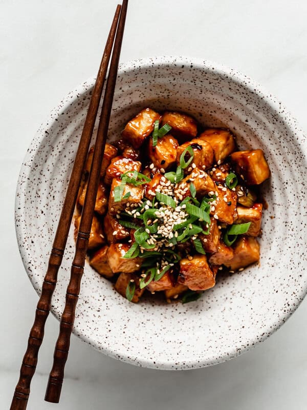 General Tso Tofu in a speckled ceramic bowl with wooden chopsticks on the side