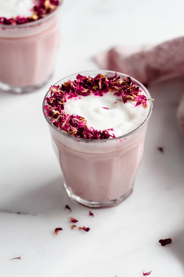 a clear glass filled with a pink latte