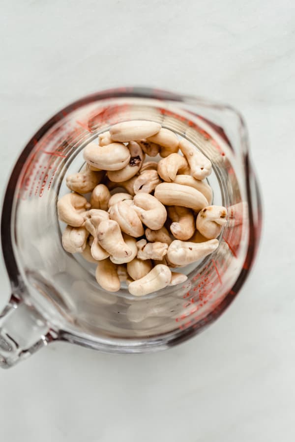 a measuring cup with raw cashews in it