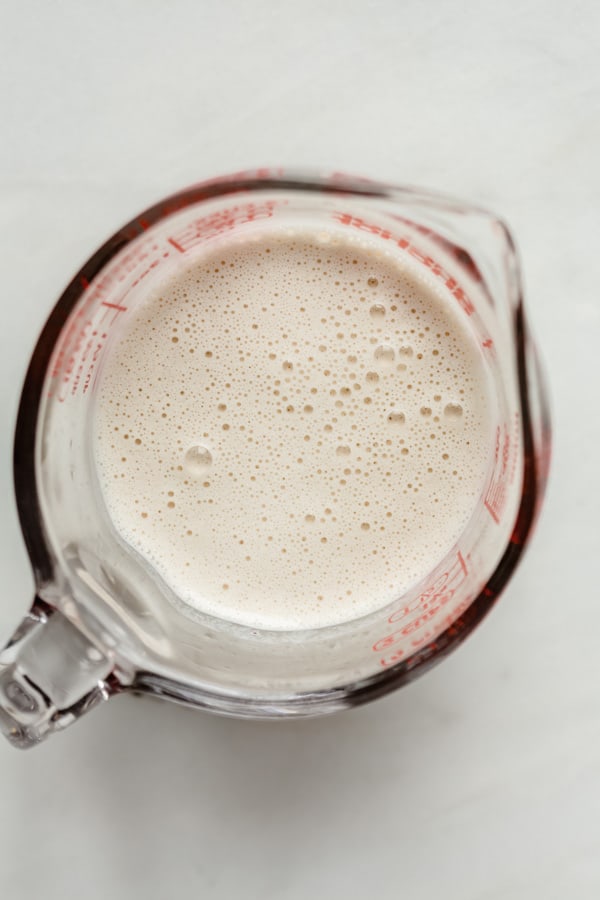 a measuring cup with cashew milk in it