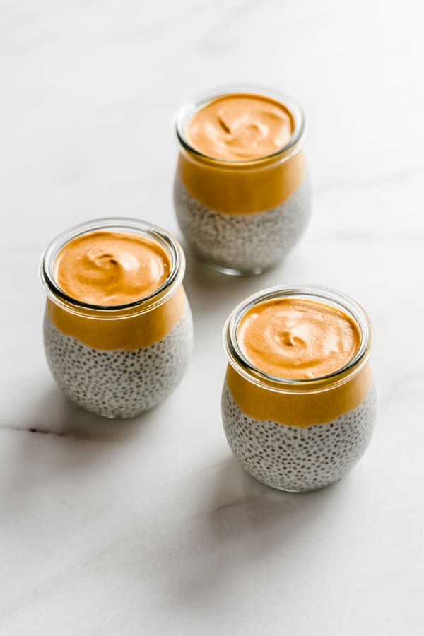 three jars filled with chia pudding and topped with pumpkin mousse