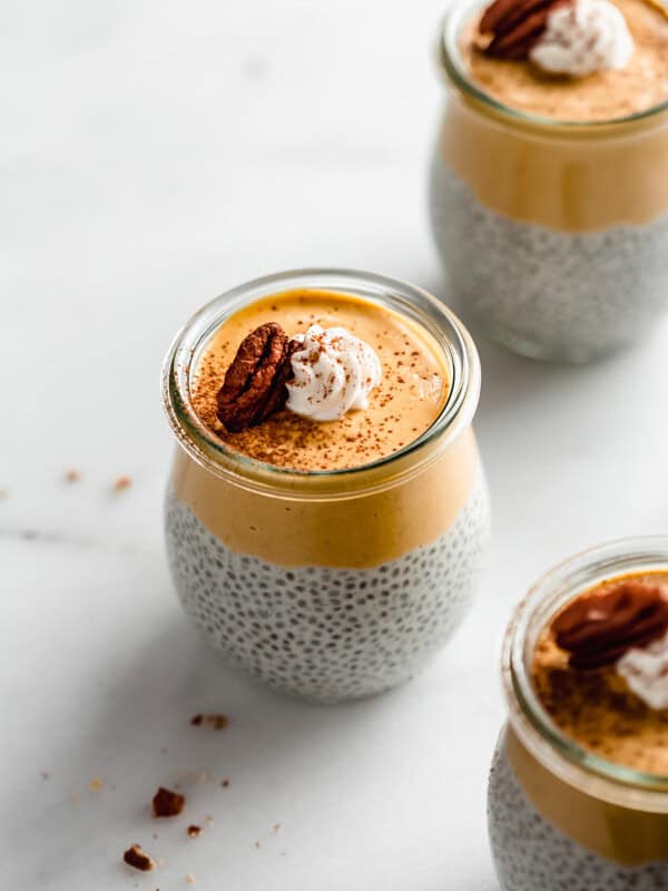 a small jar of pumpkin pie chia pudding topped with whipped cream and a pecan
