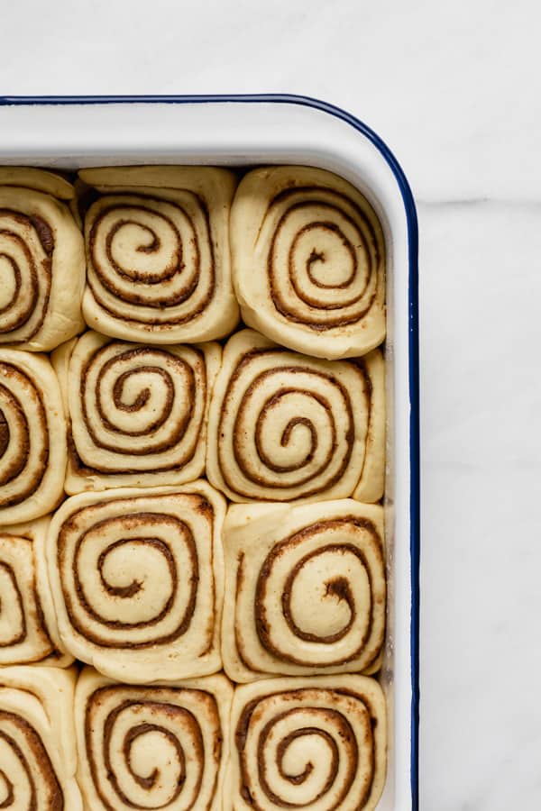 a white enamel baking pan with unbaked cinnamon rolls in it
