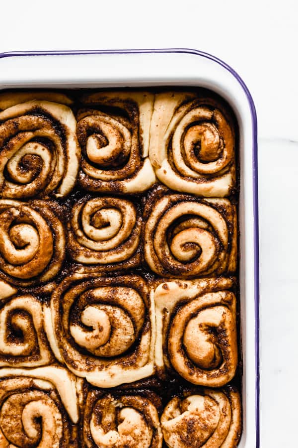 a white enamel baking pan with baked cinnamon rolls in it