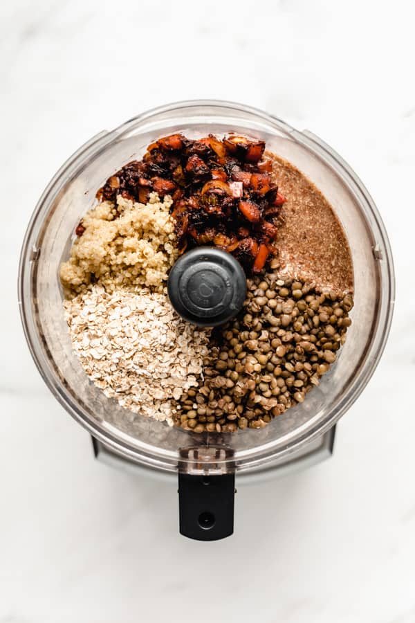 A food processor with veggies, lentils, flax oats and quinoa in it