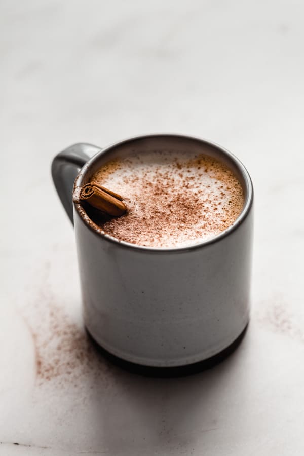 a blue and grey ceramic mug filled with a pumpkin spice latte topped with cinnamon