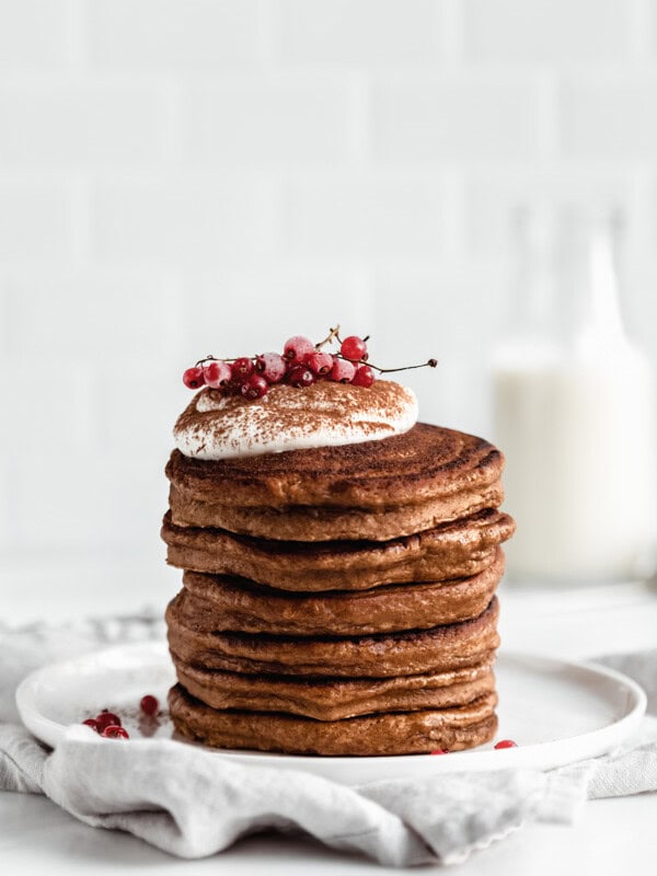 a stack of gingerbread pancakes topped with yogurt and currants