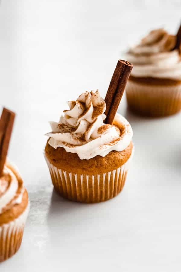 a pumpkin spice latte cupcake topped with sprinkled pumpkin spice and a cinnamon stick