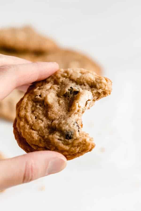 a hand holding a chewy white chocolate cranberry cookie with a bite taken out of it