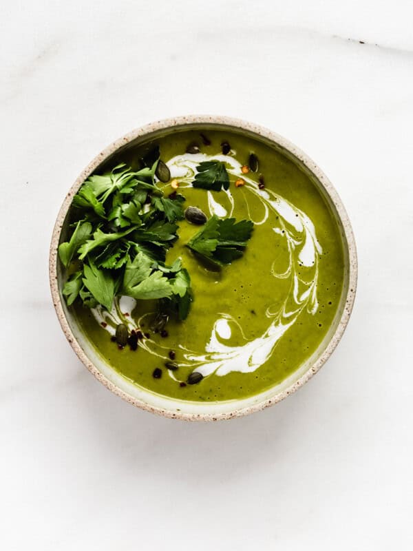 a bowl of broccoli soup topped with coconut milk and parsley