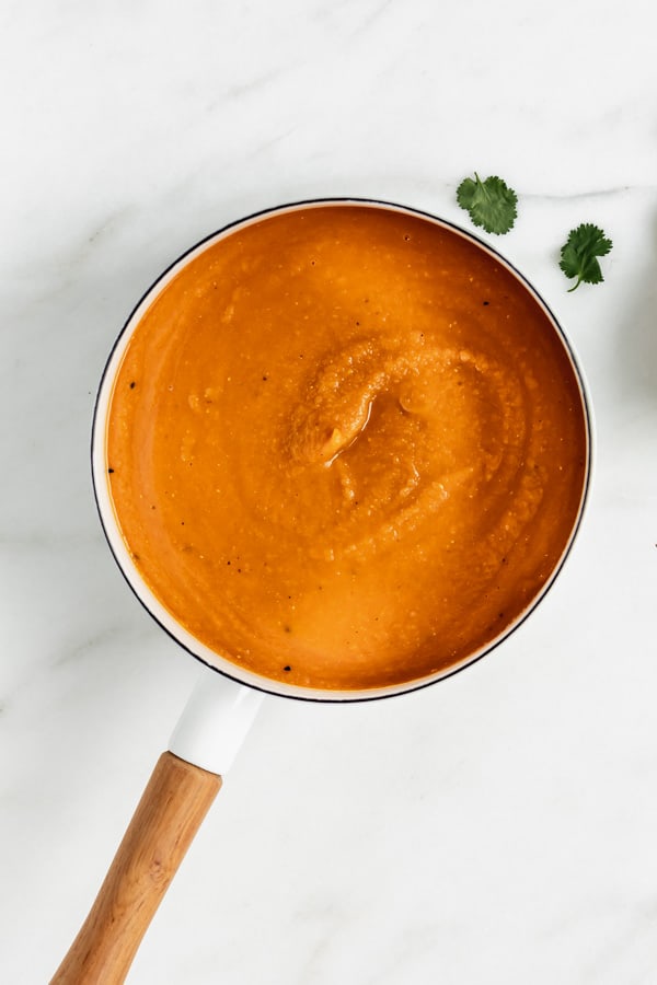 a white pot filled with carrot, lentil sweet potato soup