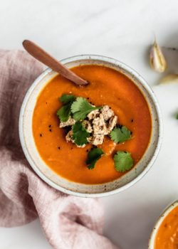 A bowl of carrot, lentil and sweet potato soup with Ryvita crisp breads crumbled on top