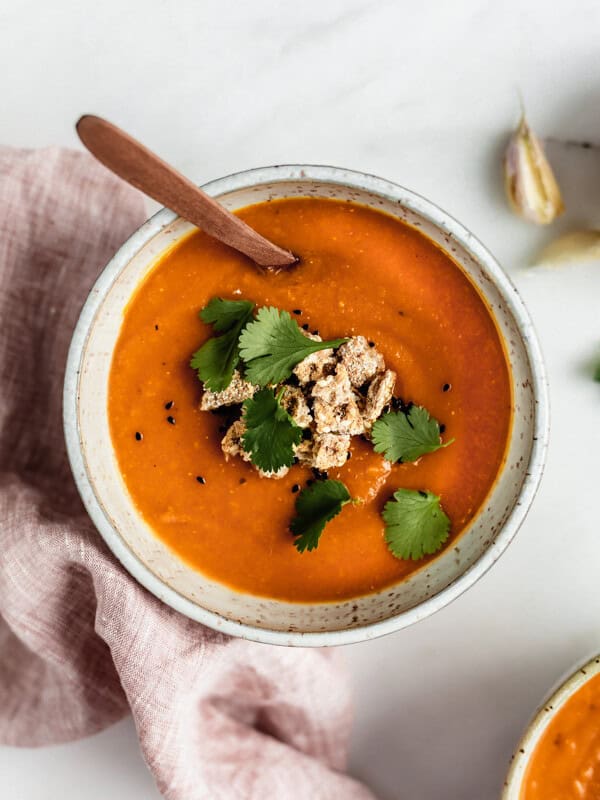 A bowl of carrot, lentil and sweet potato soup with Ryvita crisp breads crumbled on top