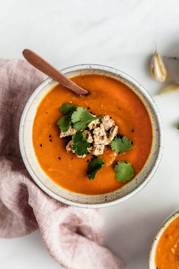 A bowl of carrot, lentil and sweet potato soup with Ryvita crisp breads crumbled on top