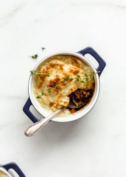 a vegan lentil shepherd's pie in a small blue ramekin with a spoon in it