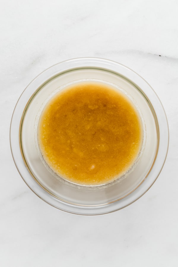 mashed banana, coconut oil and maple syrup in a clear mixing bowl
