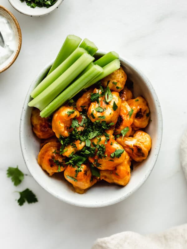 buffalo cauliflower wings in a bowl with celery on the side