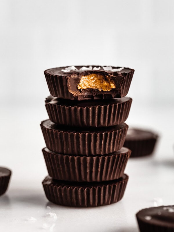 a stack of dark chocolate almond butter cups with the top one missing a bite out of it