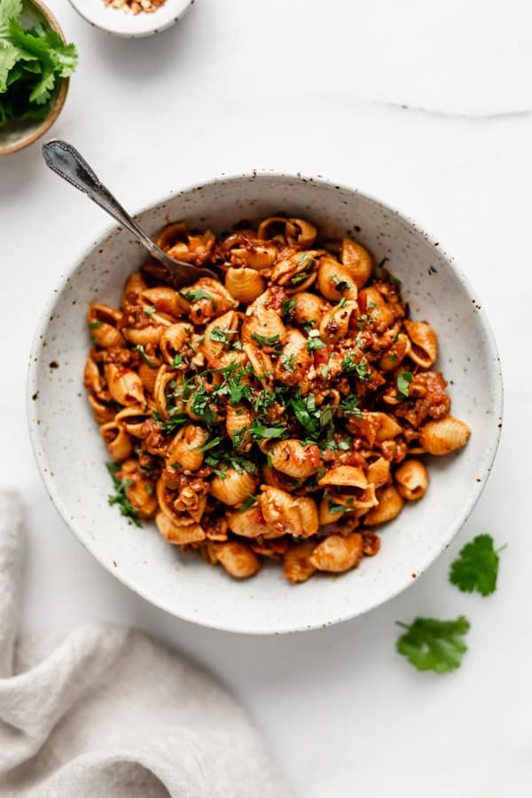 Vegan taco pasta in a bowl with a side of cilantro and a napkin on the side