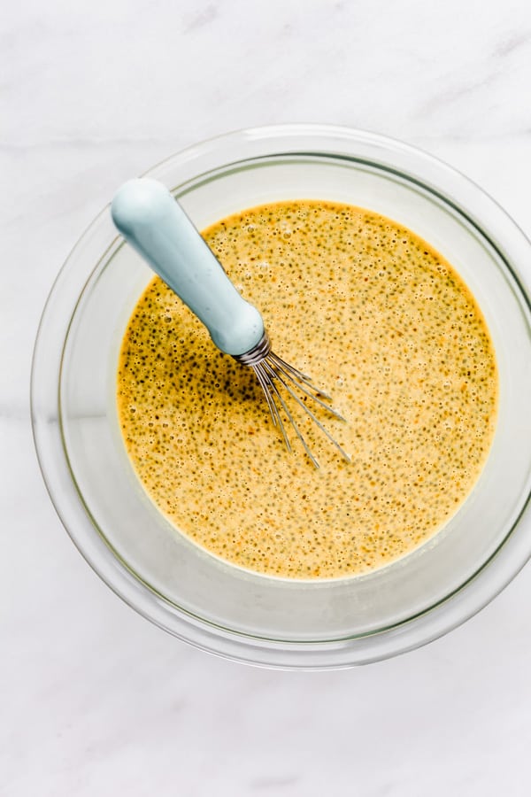 a clear mixing bowl with a chia pudding and a whisk in it