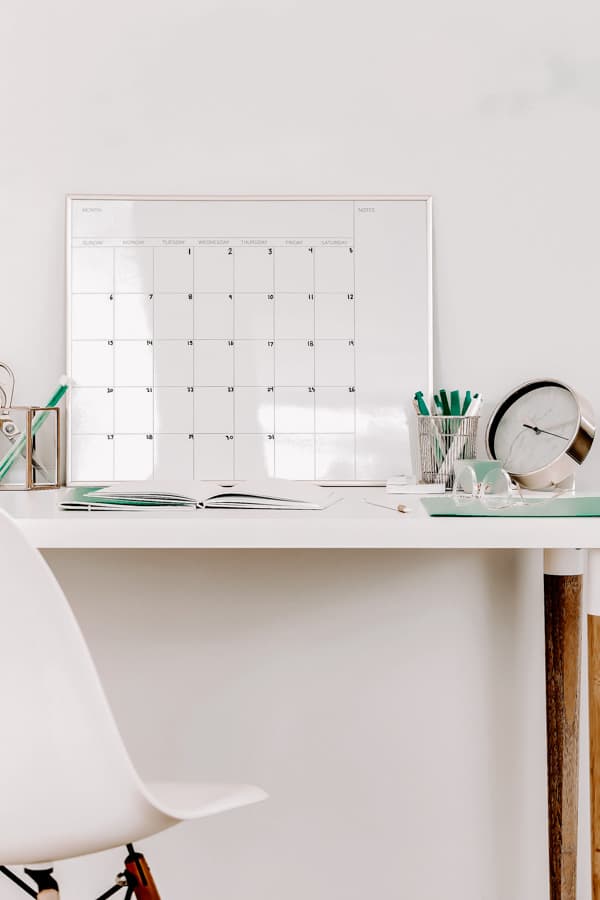 A calendar and notebook on a white desk
