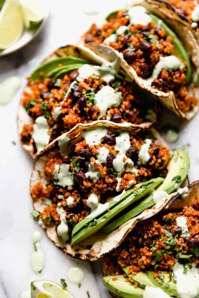 tacos filled with quinoa and a can of beans, avocados, and drizzled with a green crema