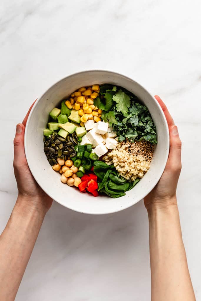 Two hands holding a bowl of salad