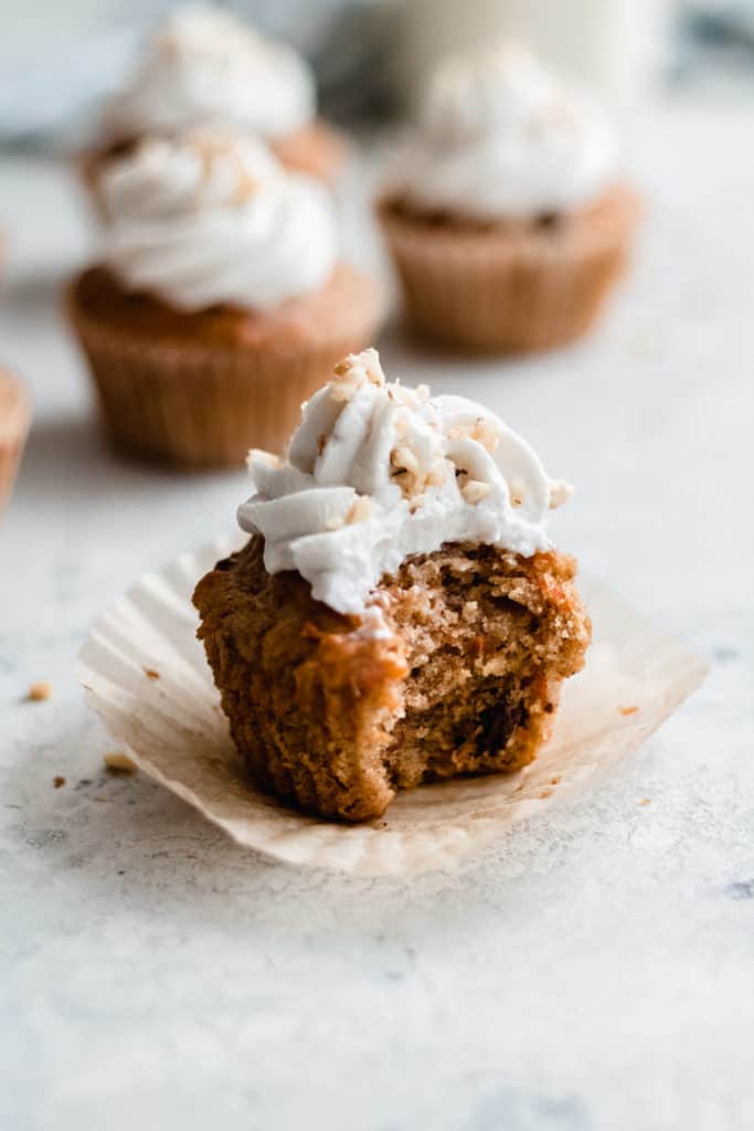 a carrot cake cupcake with a bite taken out of it