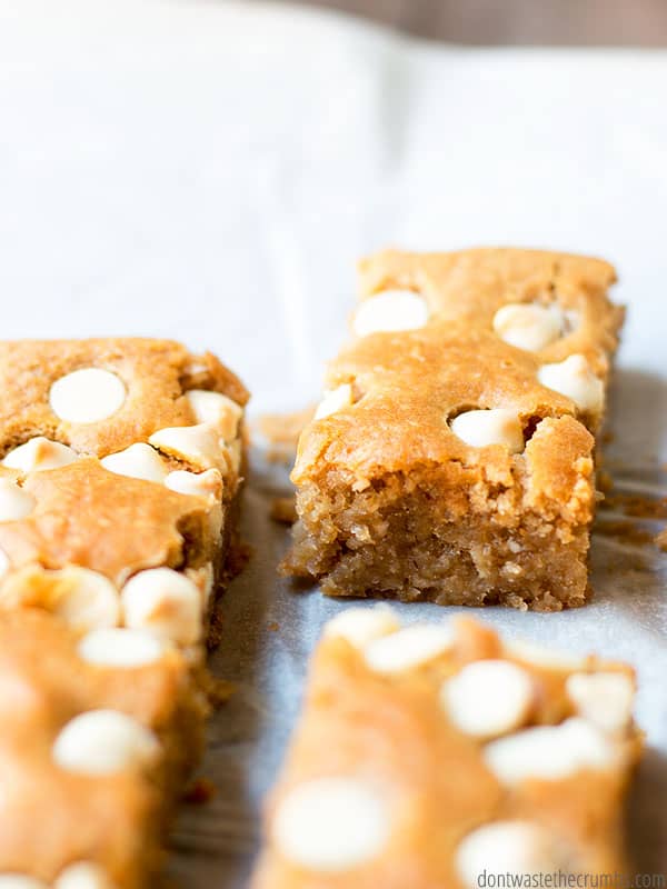 blondies made with a can of white beans, covered with white chocolate chips on a piece of white parchment paper