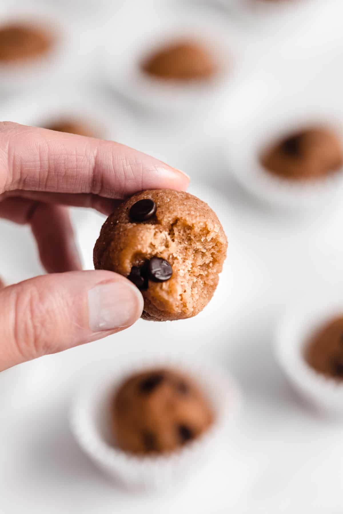 A hand holding a chocolate chip cookie dough ball