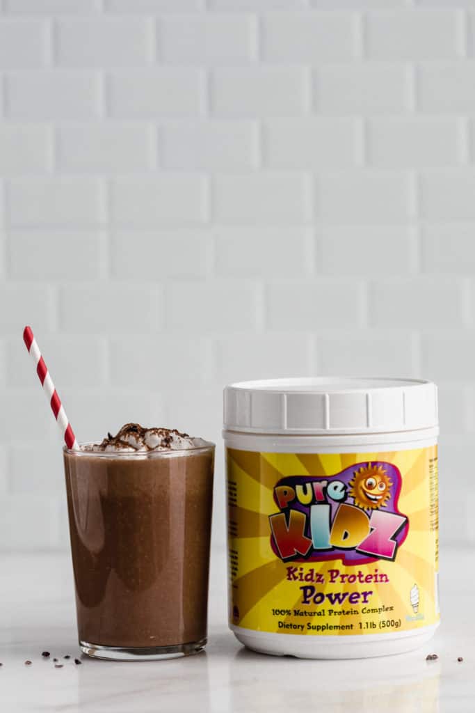 a glass of frozen hot chocolate next to a container of protein powder