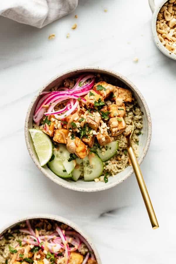A satay tofu bowl with quinoa and cucumbers